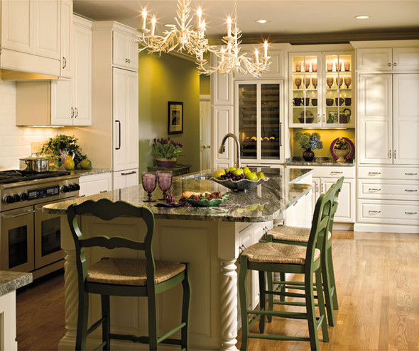 Traditional kitchen featuring white cabinets, marble counters and green chairs around an island